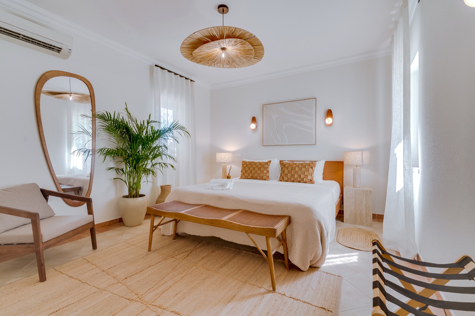 Serene white bedroom with arched mirror and natural textures at Casa da Fortuna