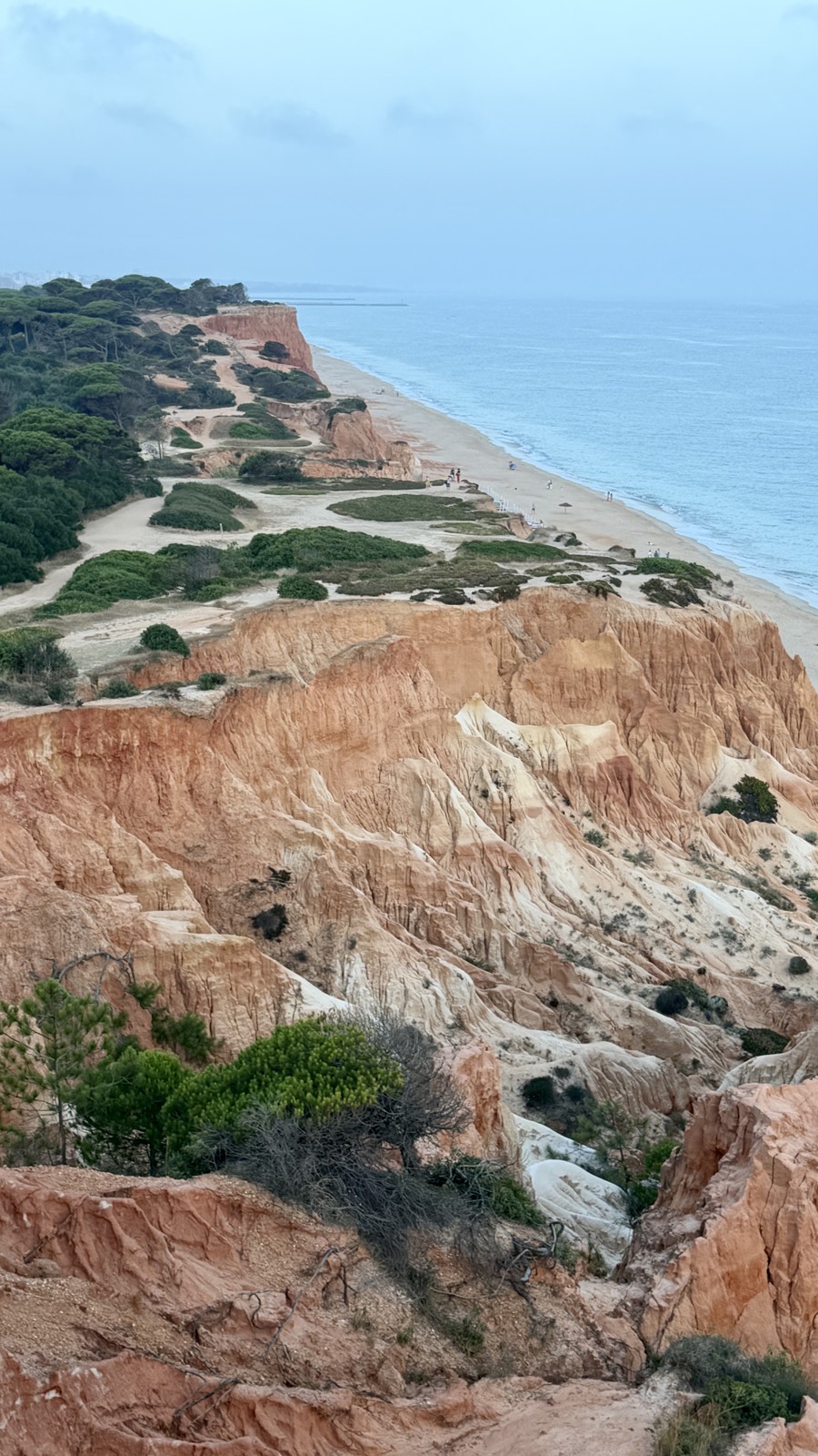 Red sandstone cliffs above golden beach and turquoise sea along the coast near the villa